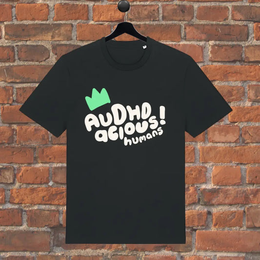 Black t-shirt with text and green logo on a hanger against a brick wall