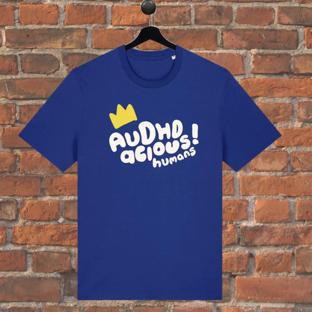Blue t-shirt with yellow crown and white text on a brick wall background