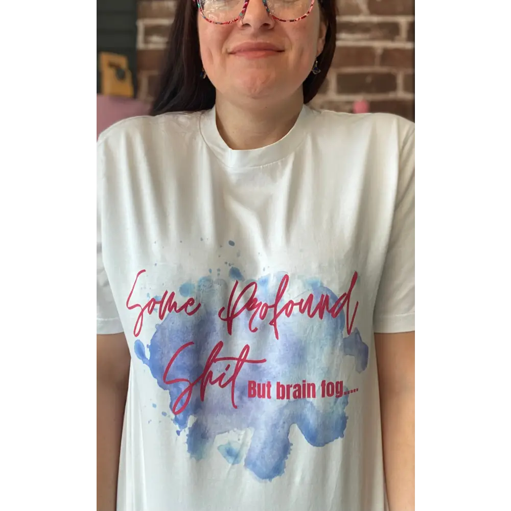 Person wearing a white t-shirt with colorful text design and watercolor pattern.