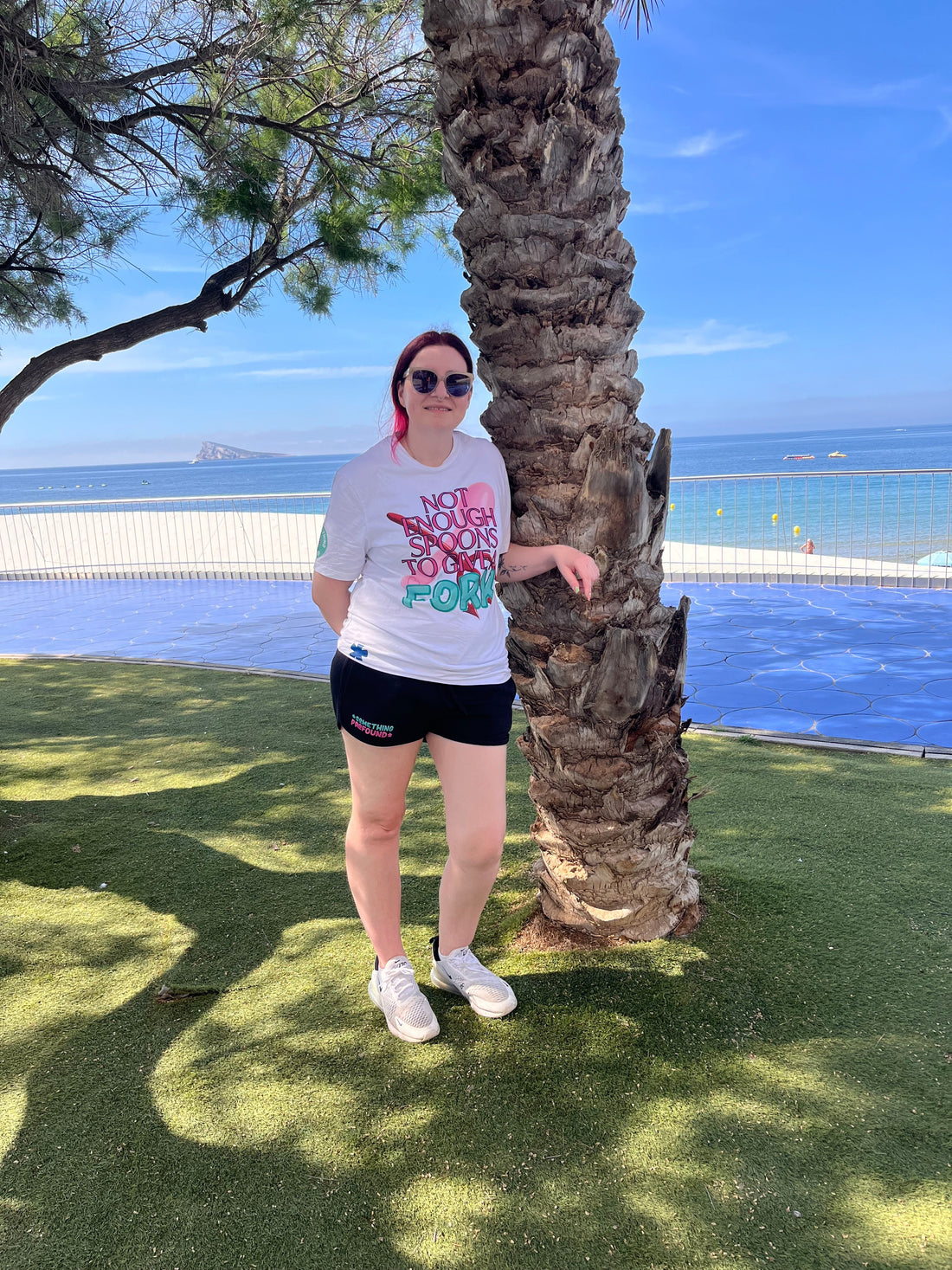 Sam In Benidorm resting on a palm tree wearing not enough spoons to give a fork t-shirt