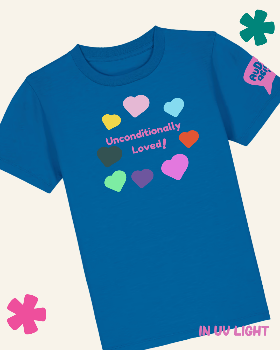 A royal blue short-sleeve t-shirt with a graphic on the front featuring colorful hearts and the text 'Unconditionally Loved!'. The shirt is displayed on a light cream background with decorative graphic overlays in the corners and a tag on the sleeve reading 'UV LIGHT'.