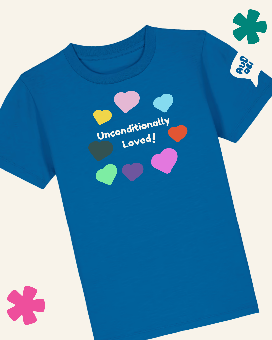 A royal blue short-sleeve t-shirt with a graphic print featuring the text 'Unconditionally Loved!' in white, surrounded by colorful pastel and bright hearts. The shirt is displayed on a light cream background with decorative graphic overlays in the corners.