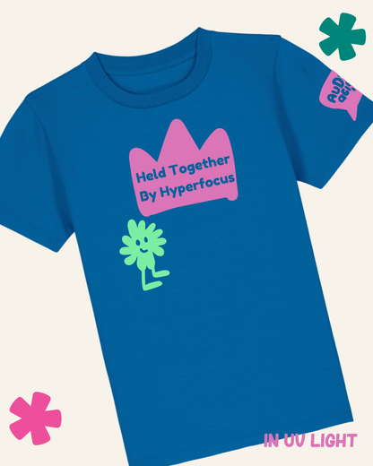 Blue t-shirt with pink crown graphic and green character, on a light gray background
