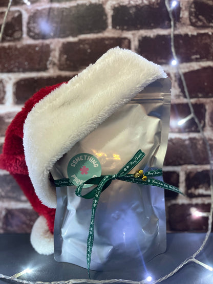 Mannequin head with red and white hood, clear bag, and green ribbon against a brick wall.