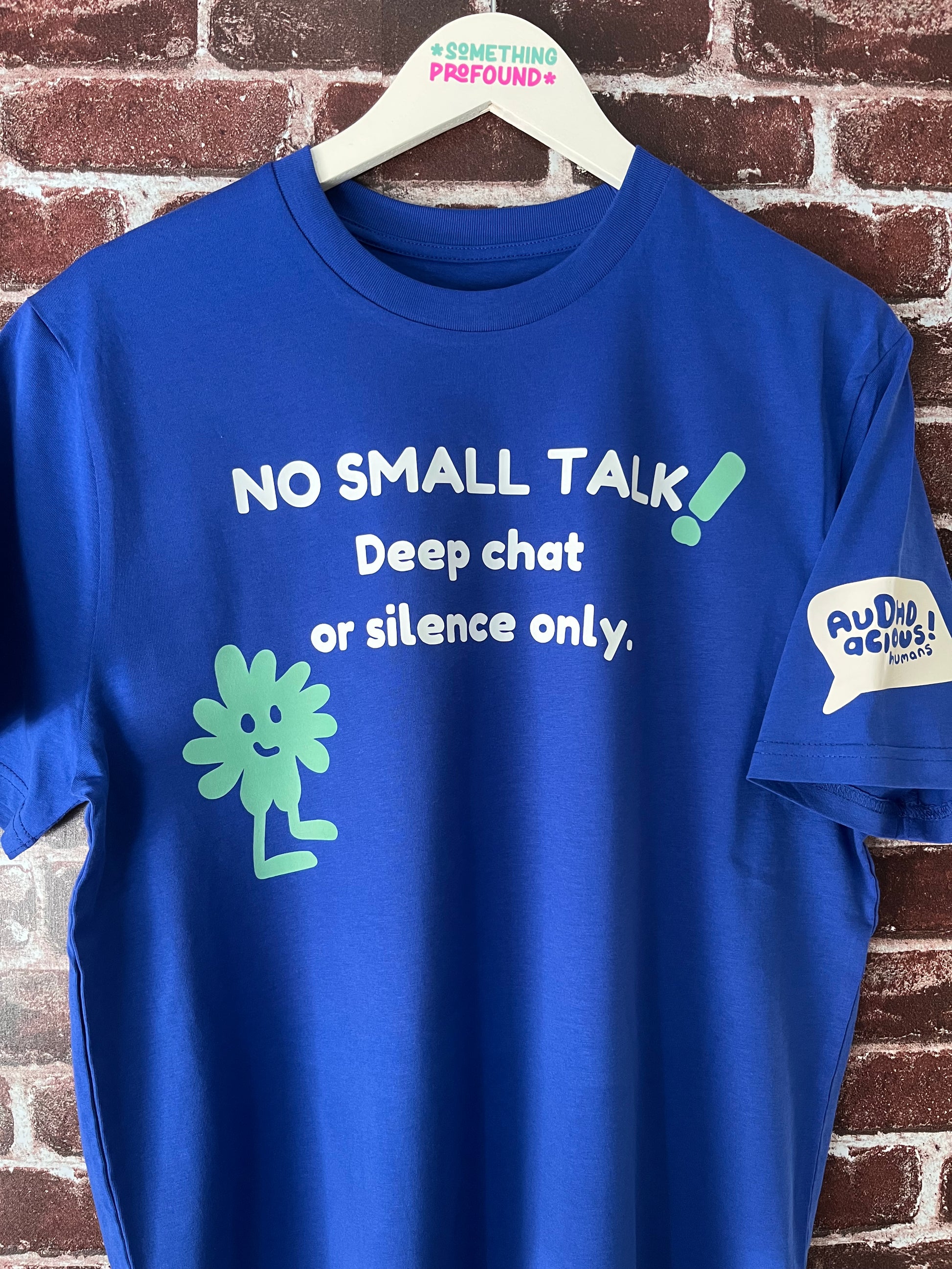Blue t-shirt with humorous text and graphics on a brick wall background