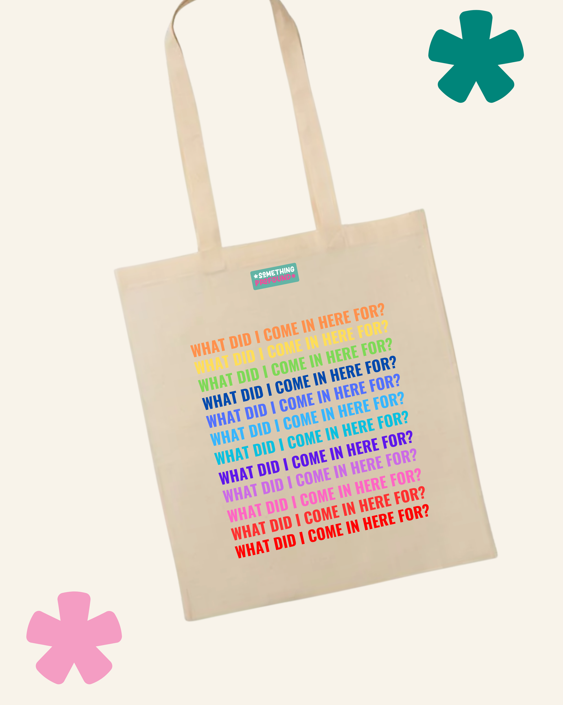 A cream-colored canvas tote bag with a colorful text graphic reading 'WHAT DID I COME IN HERE FOR?' repeated in rainbow colors. The bag is shown against a light cream background with decorative pink and teal flower graphics in the corners.