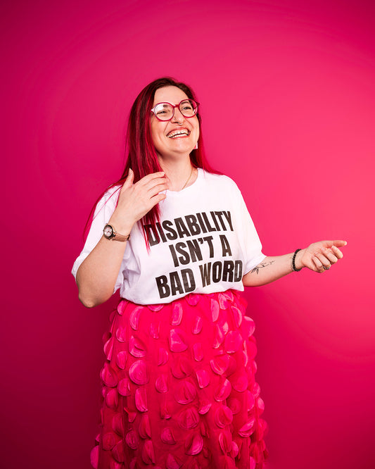 Person wearing a shirt with 'Disability Isn't a Bad Word' on a pink background photo by Haydn brown
