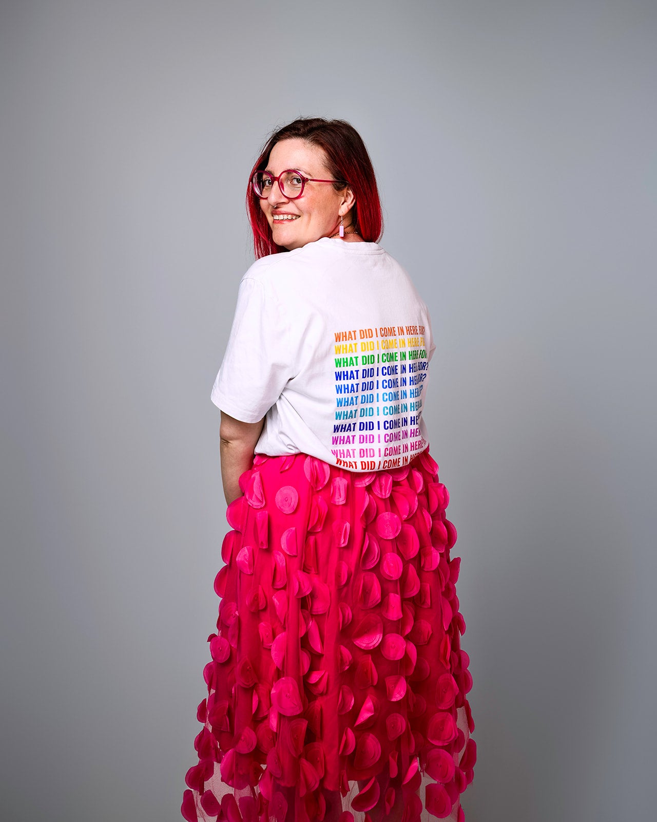 Sam wearing a white t-shirt with colourful text ‘what did I come in here for?’ and a pink skirt on a gray background photo by Haydn brown