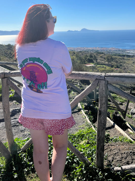 Sam standing on a wooden platform with a scenic background wearing take your negative energy and fk off pink tee
