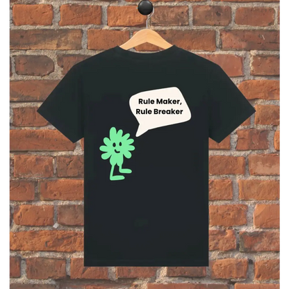 Black t-shirt with green character and text 'Rule Maker, Rule Breaker' on a wooden hanger against a brick wall.
