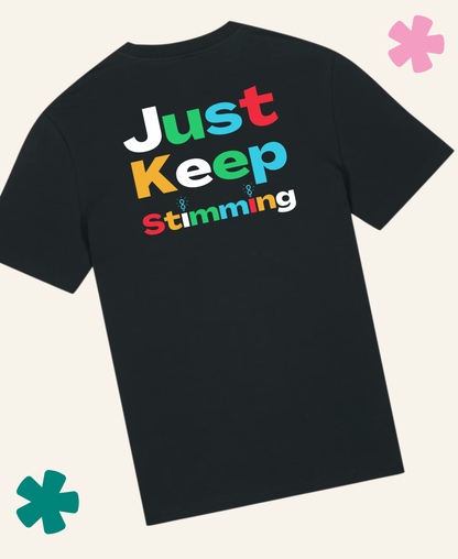 A black short-sleeve t-shirt with a colorful retro-style graphic text reading 'Just Keep Stimming' on the back, displayed on a light cream background with decorative teal and pink flower graphics in the corners. Unite Club x Something Profound