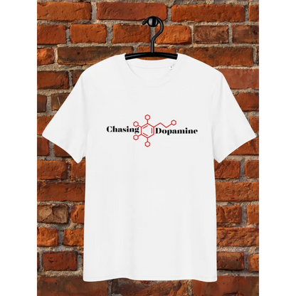 White t-shirt with 'Chasing Dopamine' design on a hanger against a brick wall.