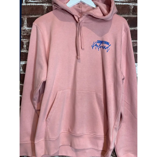 Pink hoodie with blue text on a brick surface