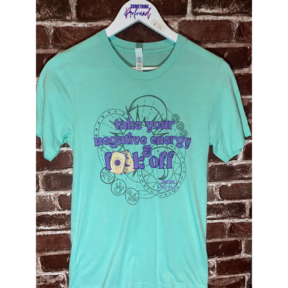 Mint green t-shirt with graphic design and text on a brick wall background