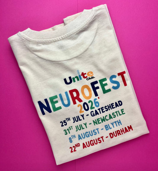 A folded off-white t-shirt with a colorful 'NeuroFest 2026' event graphic, laid flat on a vibrant pink background.